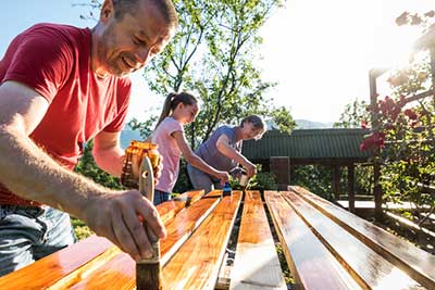 A family of three staining planks of wood for outdoor project