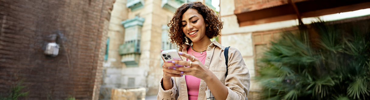 Smiling woman using her new phone while traveling