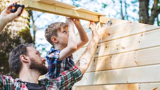 Father and son outdoors, measuring wood soon to be cut for a wood working project.