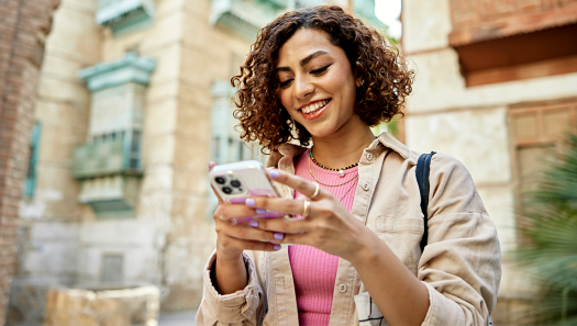 Smiling woman using her new phone while traveling